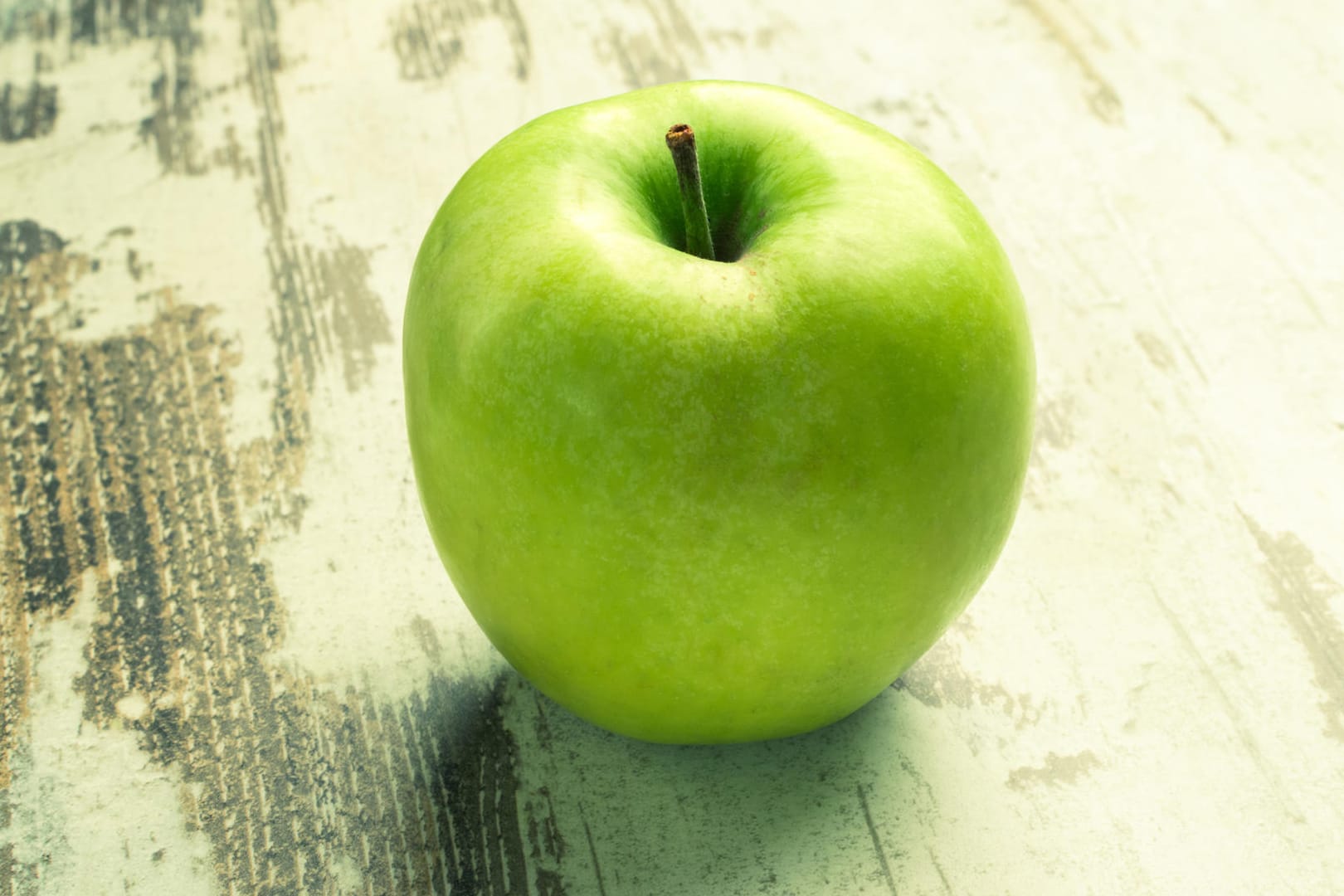 Ein grüner Apfel liegt auf einem Tisch.