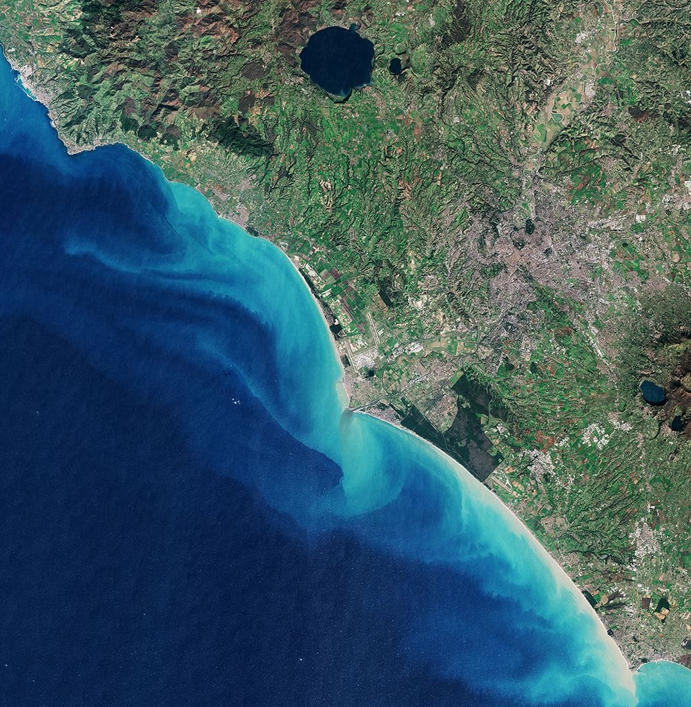 Das Satellitenbild zeigt die italienische Hauptstadt Rom. Südlich der Tiber-Mündung ins Mittelmeer erkennt man den Strand von Ostia, etwas darüber den Flughafen Fiumicino. Links oben im Bild liegt der Hafen von Civitavecchia, von dem Fähren auf Mittelmeerinseln wie Sardinien oder Sizilien ablegen.