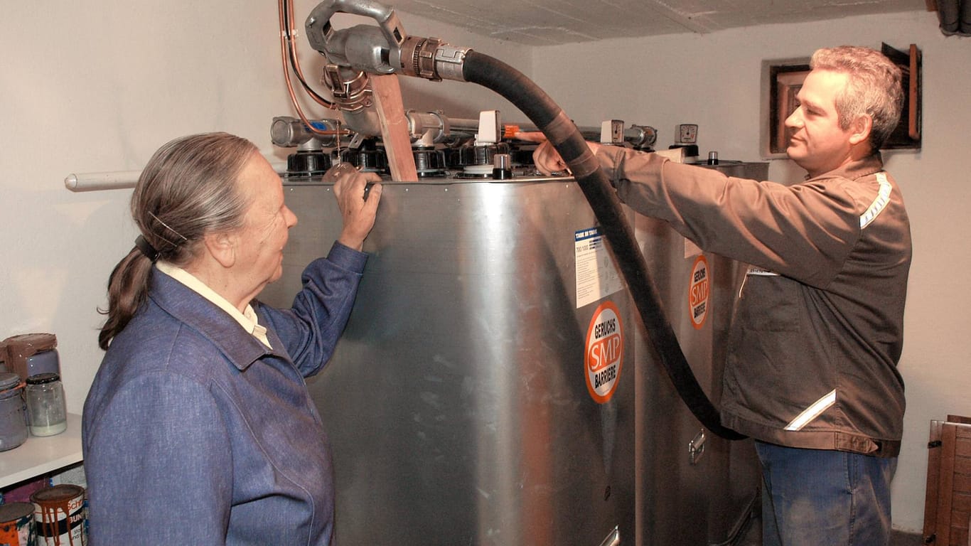 Ein Mann befüllt die Heizöltanks einer älteren Dame: In den meisten Häusern wird die Ölheizung aus einem Tank im Keller gespeist.