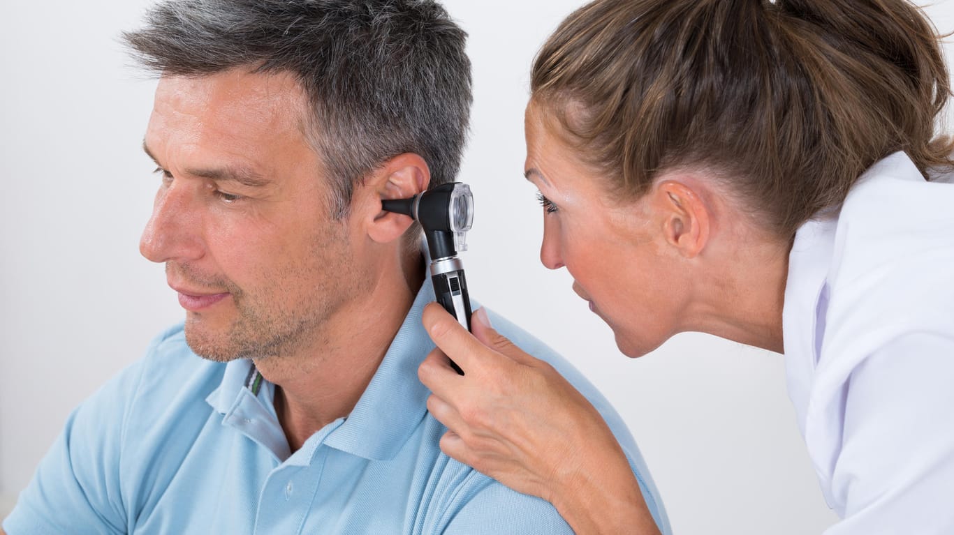 Ein Arzt untersucht das Ohr eines Mannes
