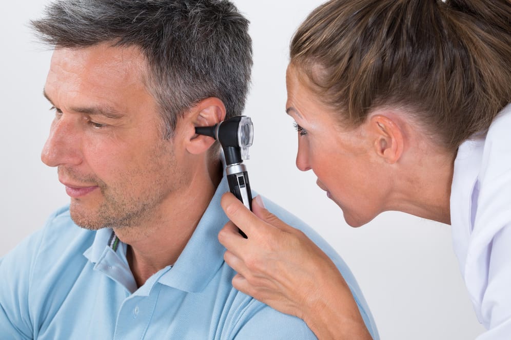 Ein Arzt untersucht das Ohr eines Mannes