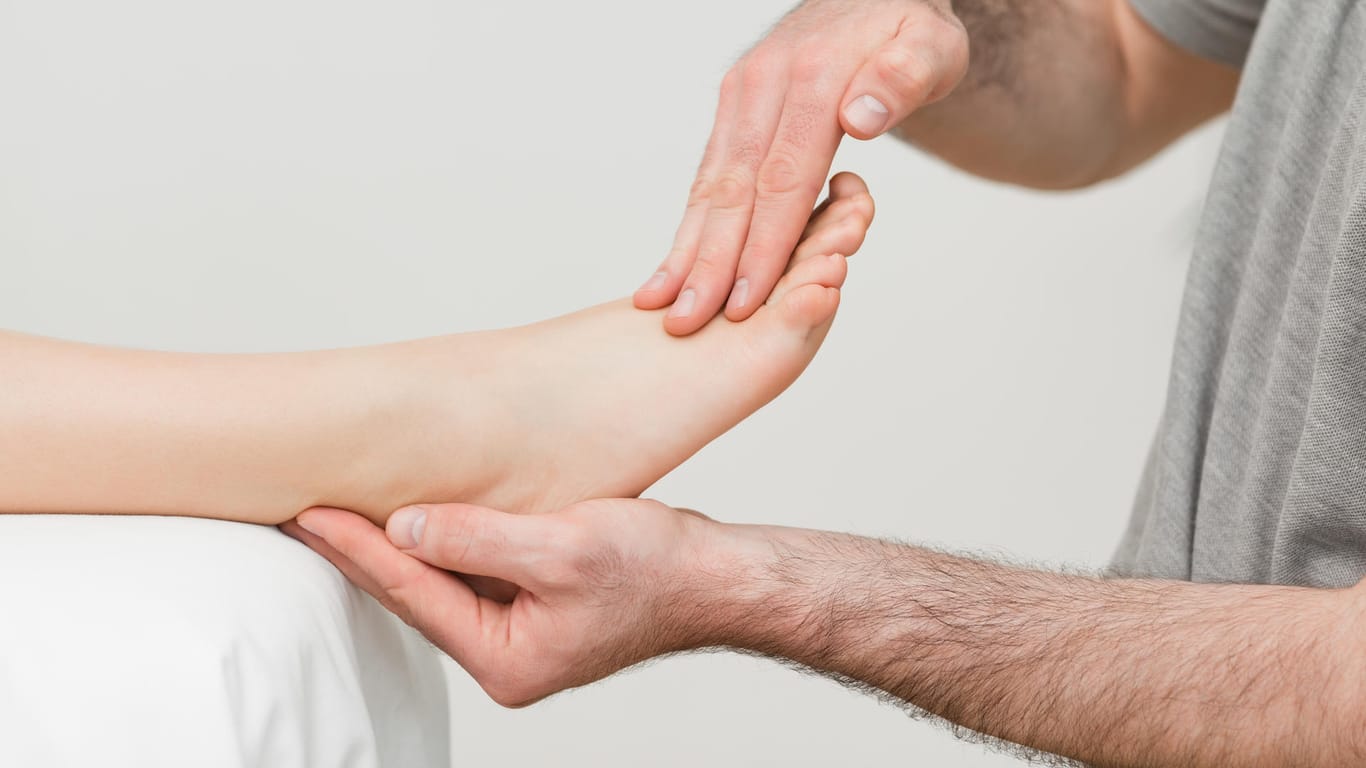 Arzt massiert Füße einer Patientin