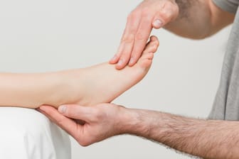 Arzt massiert Füße einer Patientin