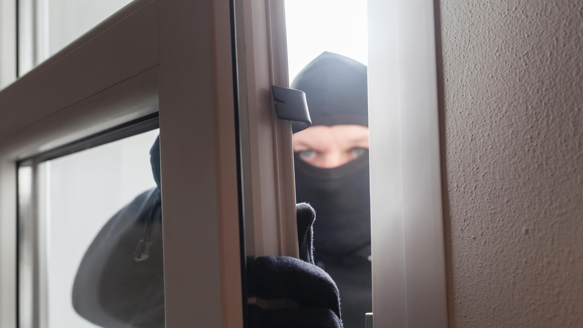 Einbrecher öffnet ein Fenster