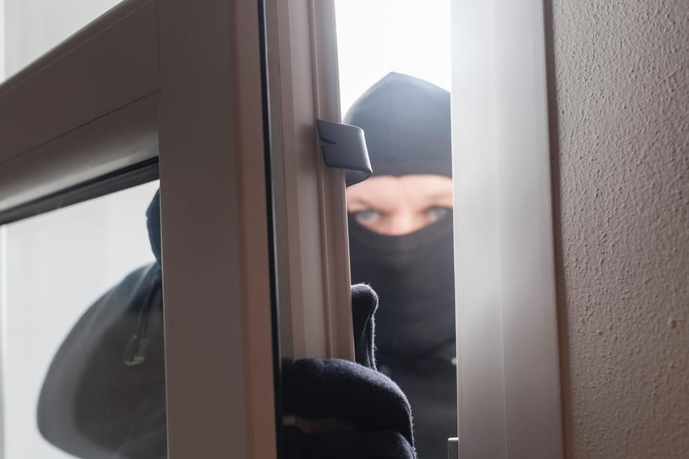 Einbrecher öffnet ein Fenster