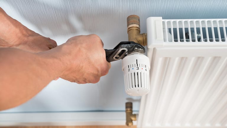 Plumber Fixing Radiator With Wrench
