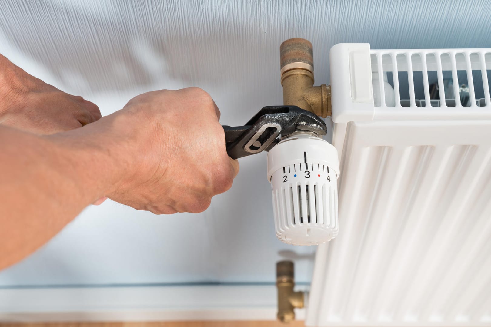 Plumber Fixing Radiator With Wrench