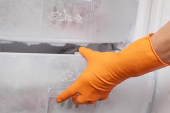 Hand in glove opening refrigerator.