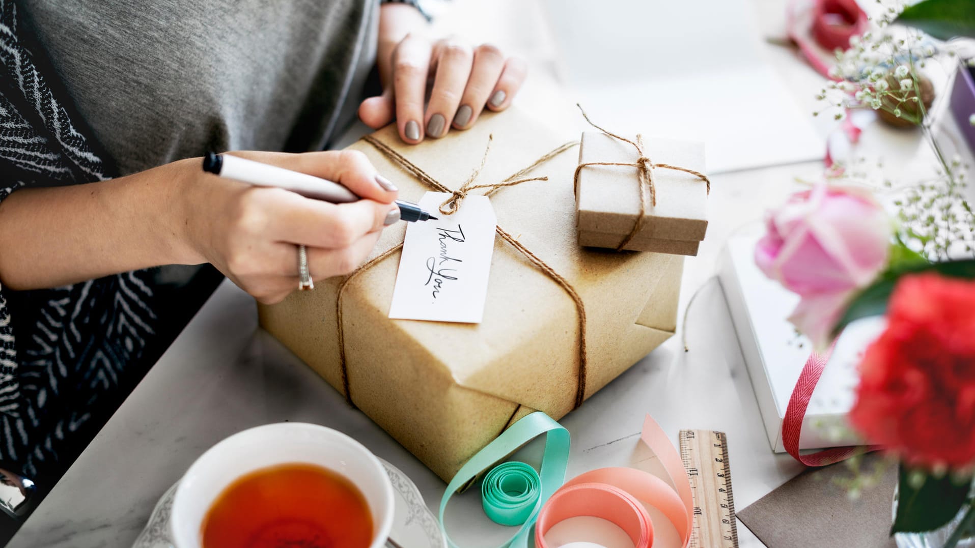 Frau schreibt eine Karte an einem Geschenkkarton