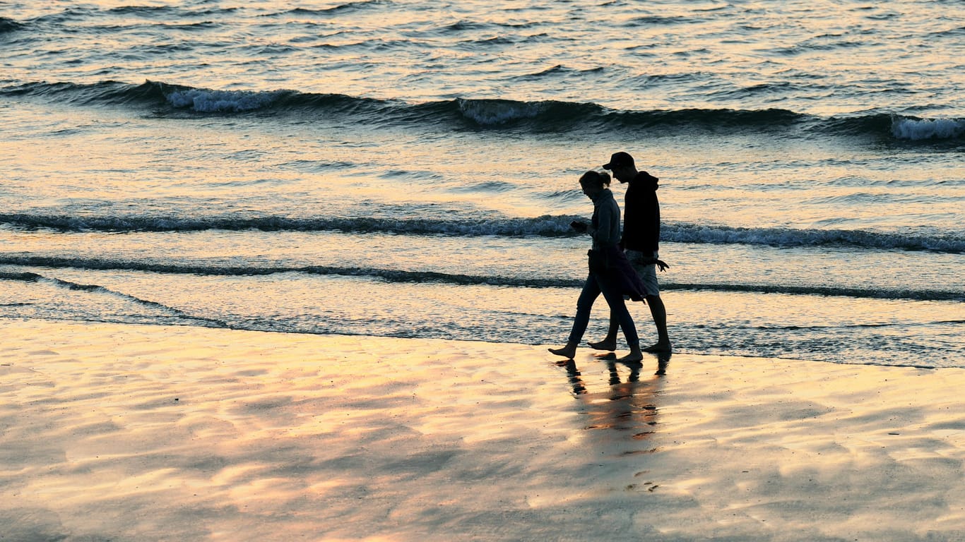 Ein Paar spaziert am Strand von Norderney: Wer unbezahlten Urlaub für eine Auszeit vom Job nehmen möchte, braucht das Einverständnis seines Chefs.