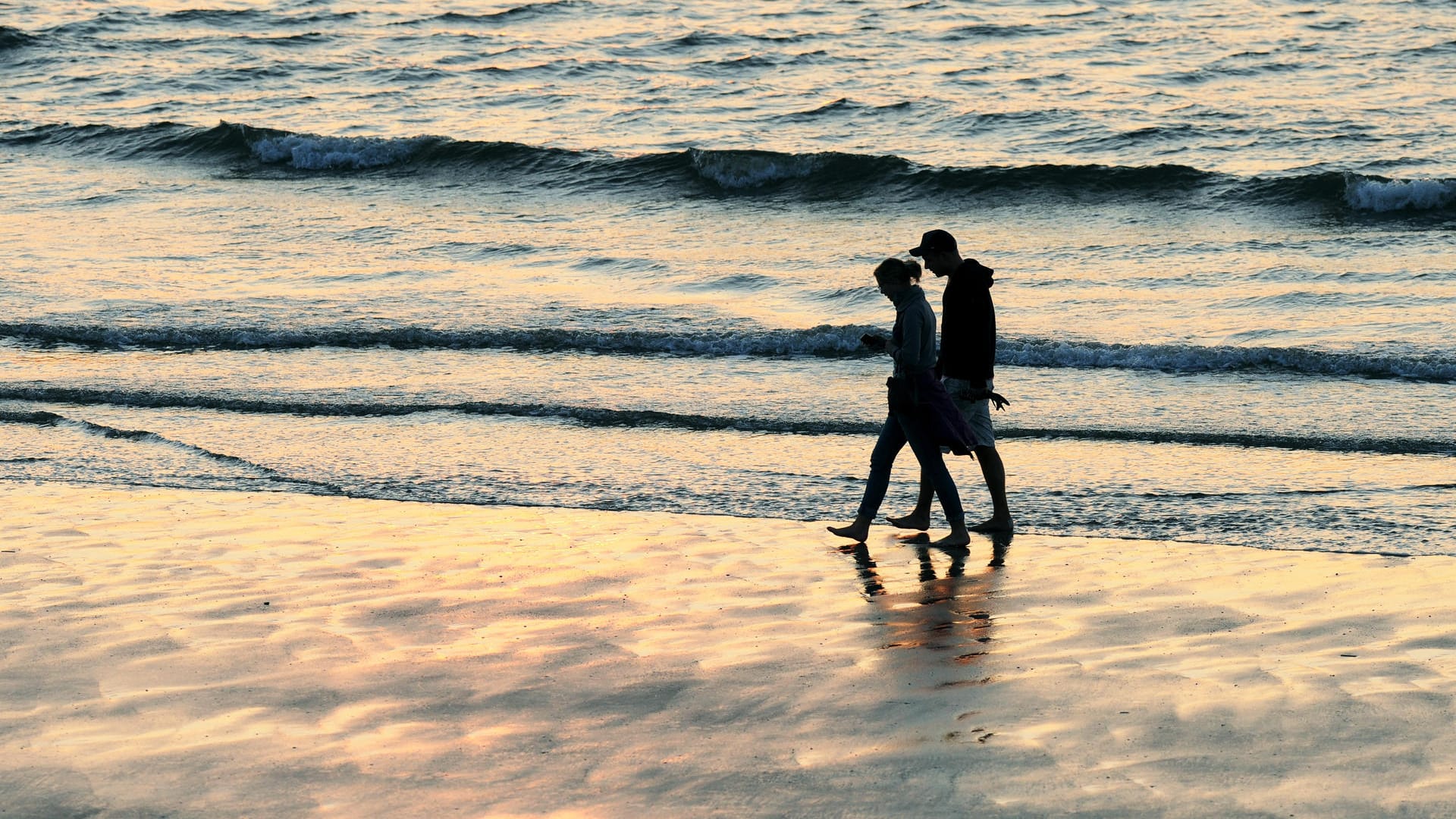 Ein Paar spaziert am Strand von Norderney: Wer unbezahlten Urlaub für eine Auszeit vom Job nehmen möchte, braucht das Einverständnis seines Chefs.