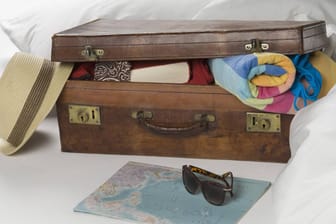 Vollgestopfter Urlaubskoffer: Wenn Sie zu viele Kleidungsstücke in einen kleinen Koffer verstauen, kann es passieren, dass dieser nicht mehr schließt.