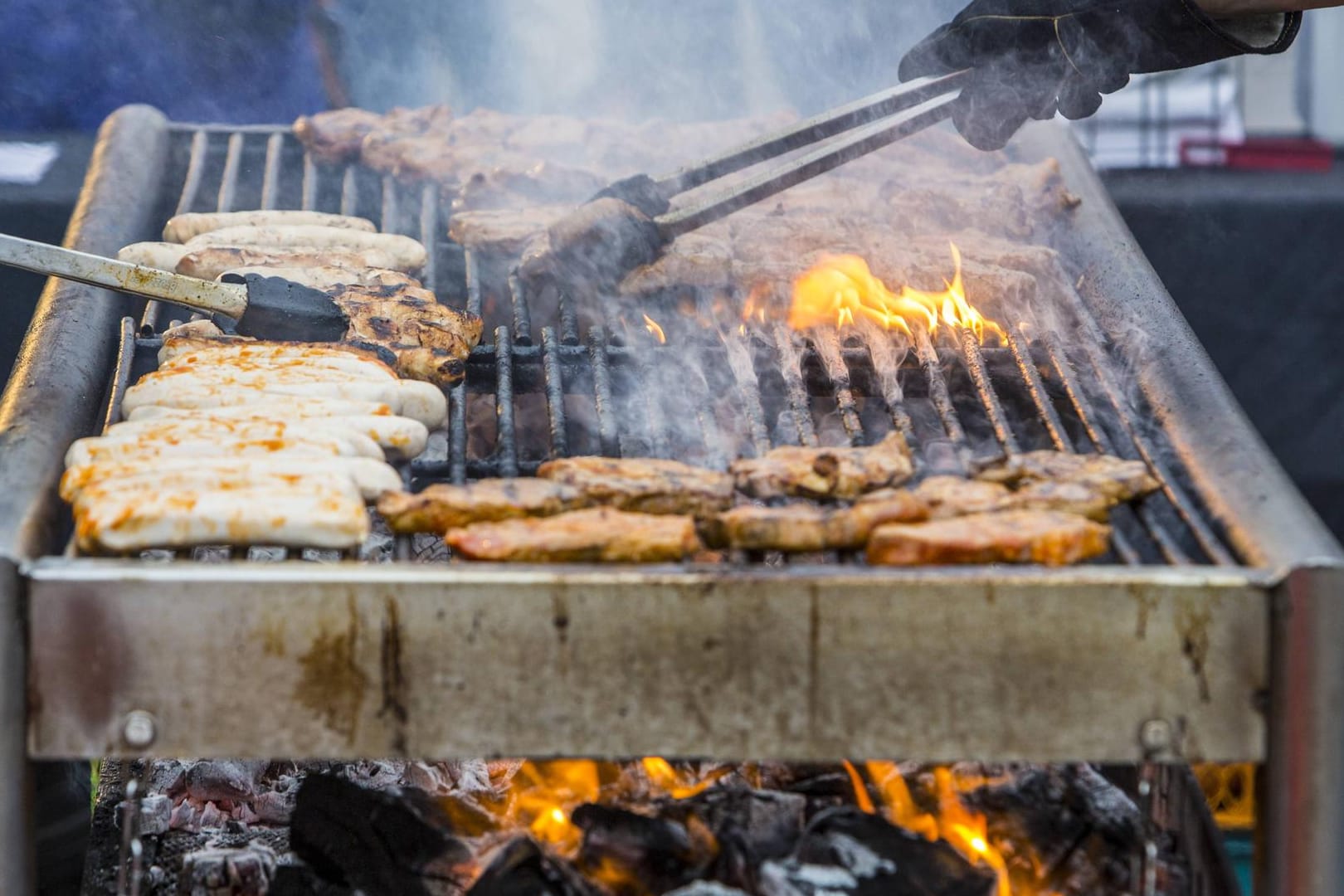 Grill Nackensteaks und Bratwürstchen werden auf einem Holzkohlengrill gegrillt