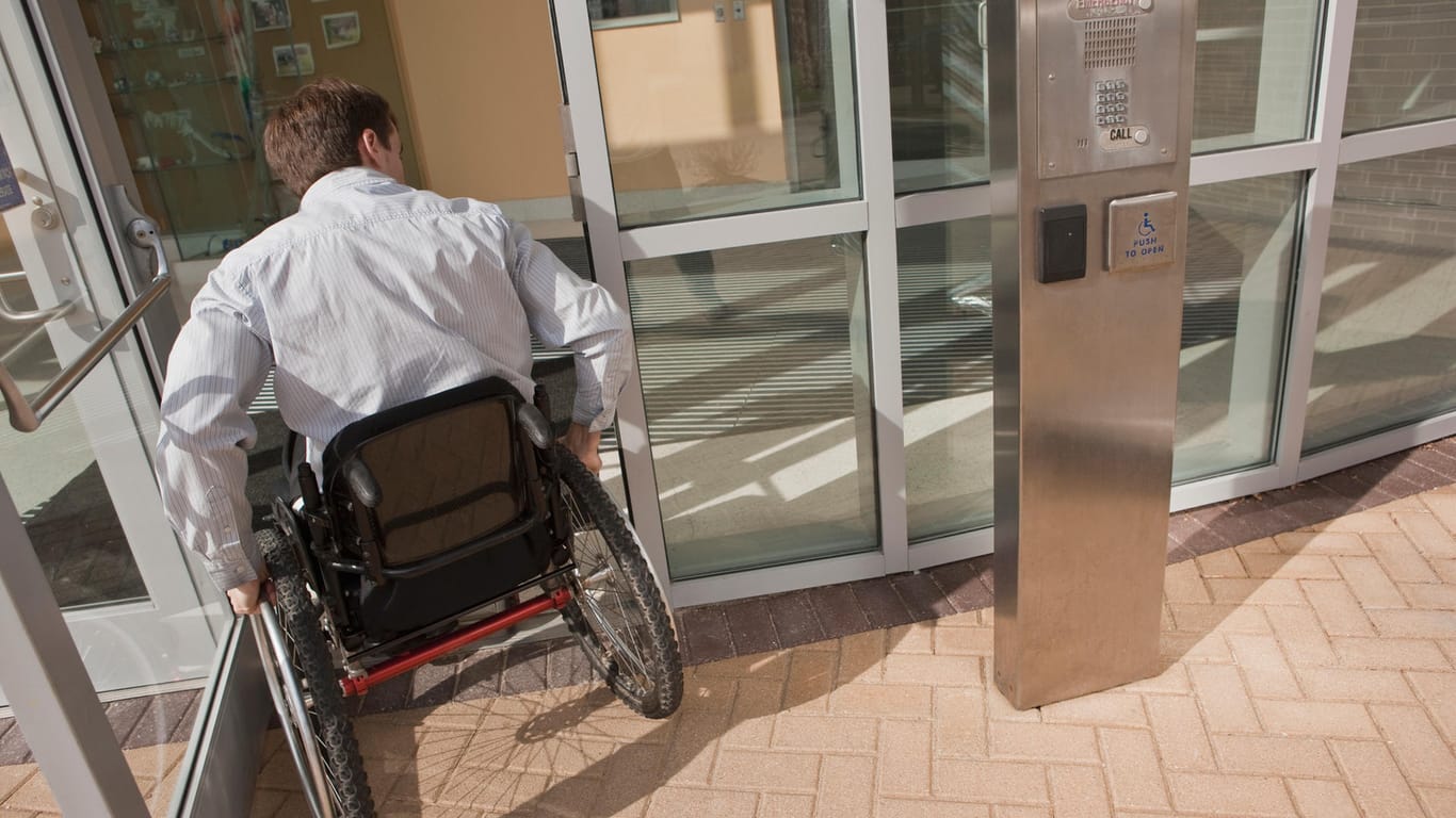 Mann im Rollstuhl fährt durch eine Eingangstür