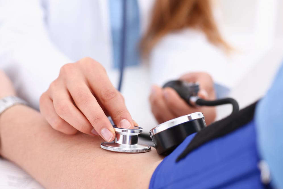 Ärztin misst den Blutdruck eines Patienten: Plötzlicher Bluthochdruck kann den Organen schaden.