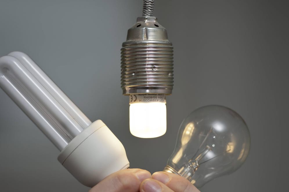 Eine LED Glühbirne leuchtet in einer Fassung während daneben eine Energiesparlampe und eine Glühlampe gezeigt werden