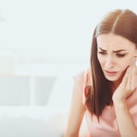 Frau mit Zahnschmerzen: Bei Weisheitszahn-Schmerzen kann eine Operation erforderlich sein.