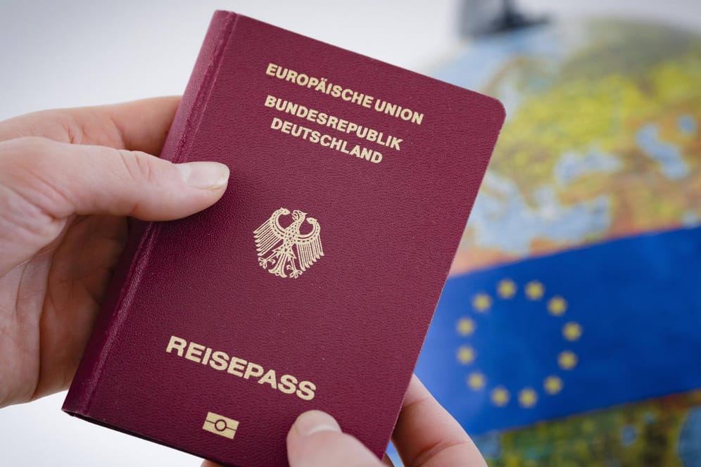 Ein deutscher Reisepass wird vor einen Globus gehalten