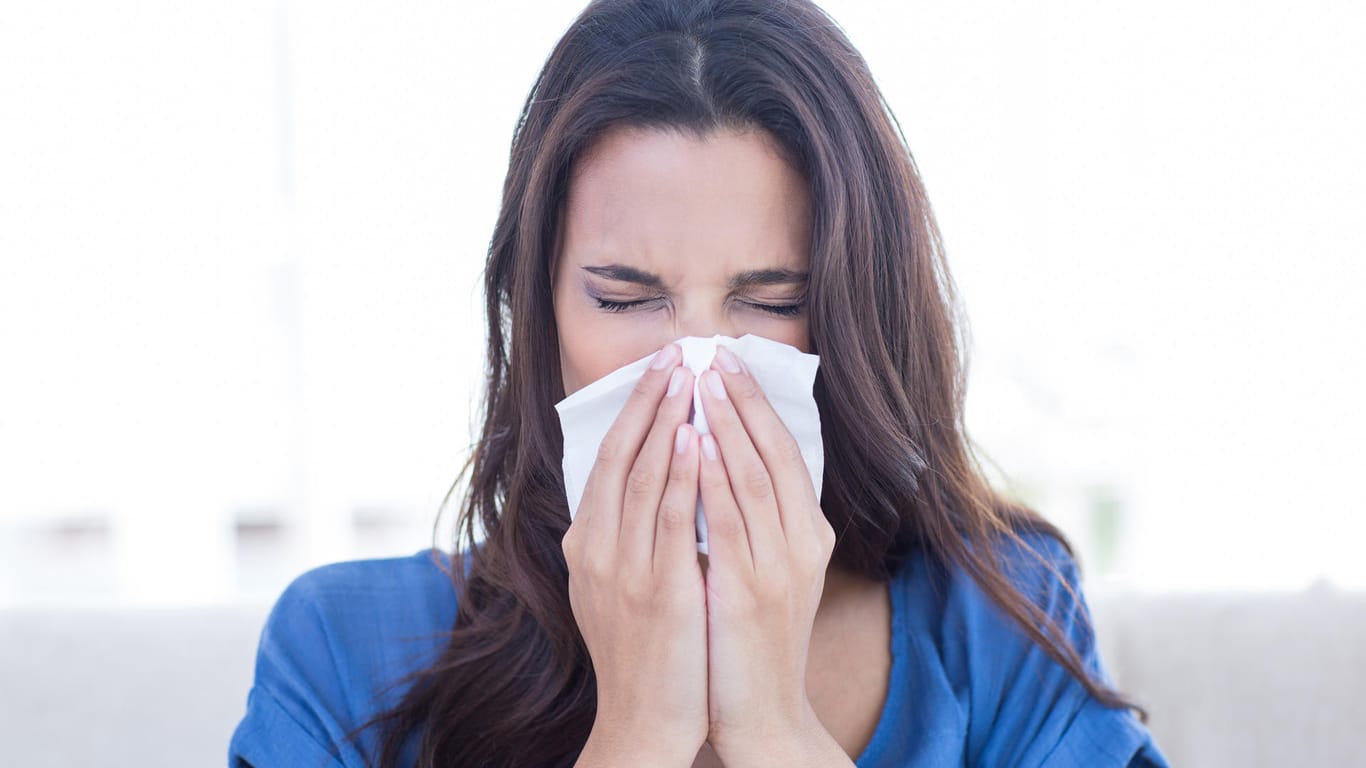 Eine Frau schnäuzt in ein Taschentuch: Grippale Infekte werden häufig über Tröpfcheninfektionen übertragen.