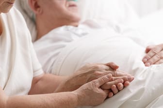Eine Frau sitzt am Sterbebett ihres Mannes: Manche Menschen berichten von Nahtoderfahrungen. Doch mit welchen Eindrücken gehen wir in den Tod?