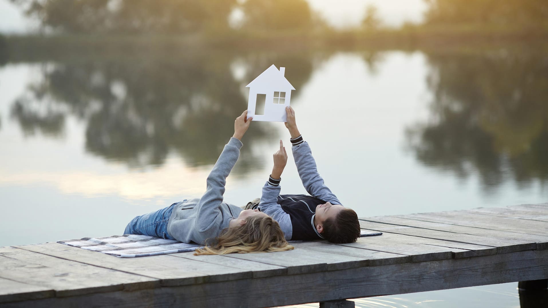 Paar mit dem Modell eines Hauses: Wer sich für die Erbpacht entscheidet, sollte mit dem Grundstücksbesitzer neben der Laufzeit, dem Pachtzins unter anderem auch die Frage der Vertragsverlängerung klären.