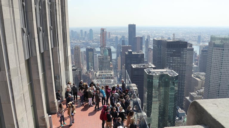 New York: Touristen stehen auf der Aussichtsplattform an der Spitze des Rockefeller Center und schauen in Richtung Empire State Building.