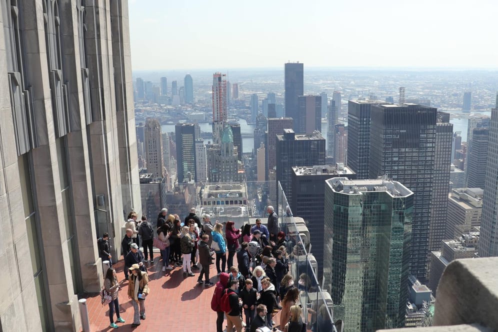 New York: Touristen stehen auf der Aussichtsplattform an der Spitze des Rockefeller Center und schauen in Richtung Empire State Building.