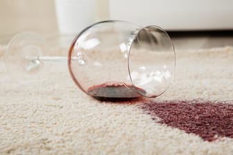 Rotwein auf Teppich verschüttet: Je frischer sie sind, desto leichter lassen sich Rotweinflecken entfernen.