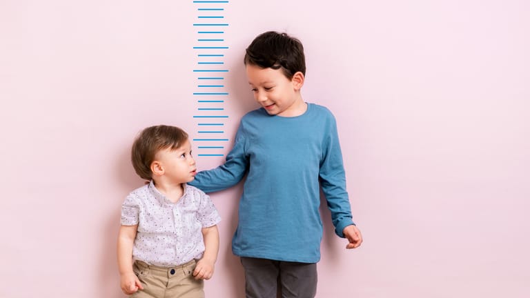Zwei Junge vor einem Zentimetermaß: Wie groß werde ich?