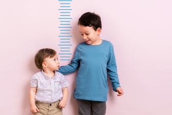 Zwei Junge vor einem Zentimetermaß: Wie groß werde ich?