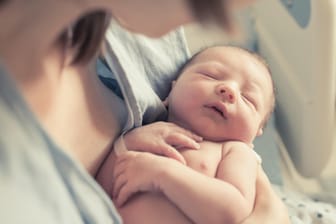 Mutter mit Neugeborenem im Arm: Babys wecken Beschützerinstinkte.