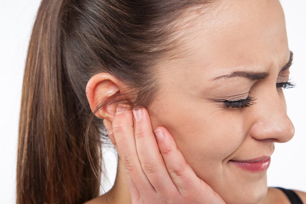 Frau mit Beschwerden am Ohr: Ein pulsierendes Geräusch im Ohr kann ein Anzeichen für Bluthochdruck sein.