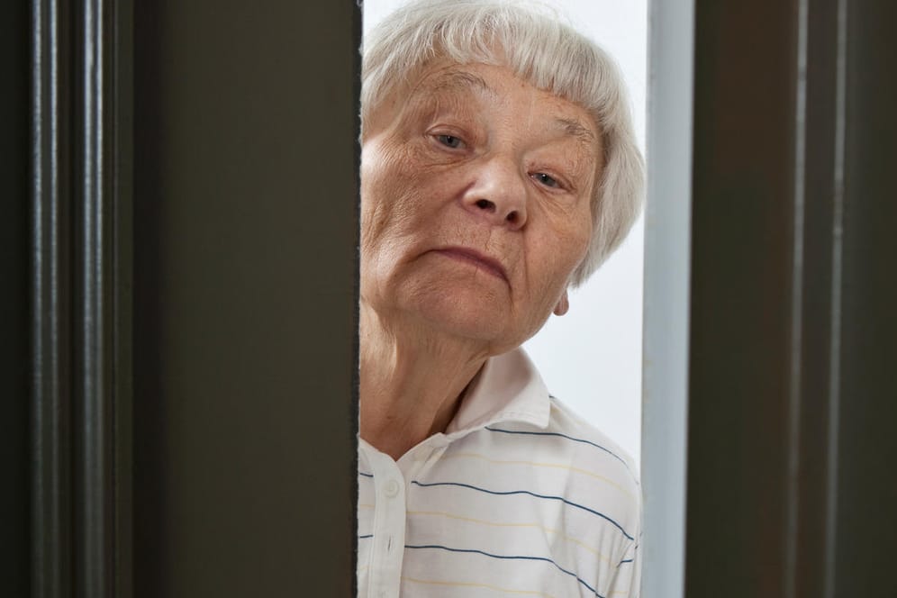 Frau öffnet Wohnungstür: Sie entscheidet, wer die Wohnung betreten darf und wer nicht.