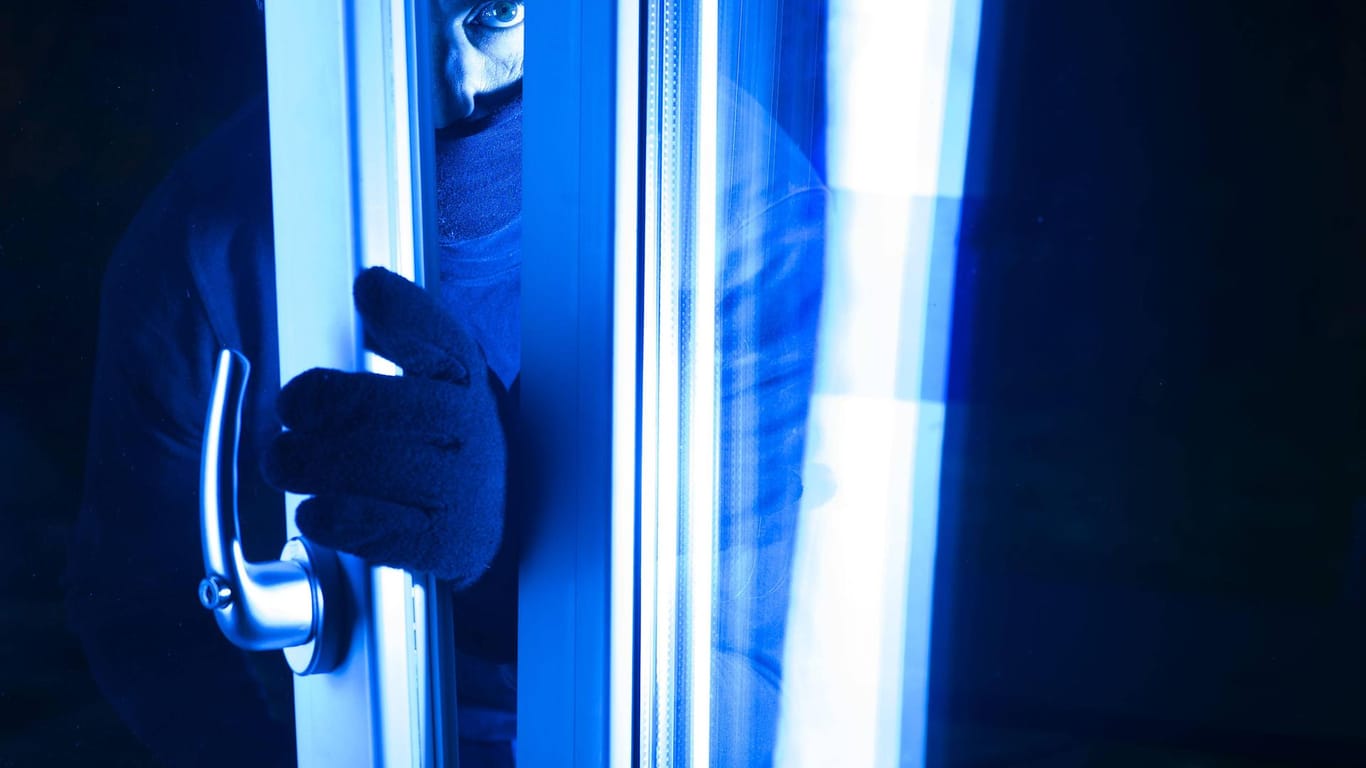 Einbrecher öffnet nachts ein gekipptes Fenster