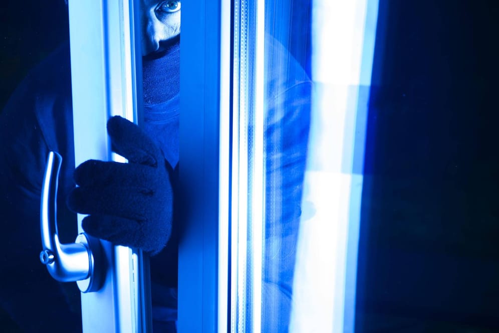 Einbrecher öffnet nachts ein gekipptes Fenster