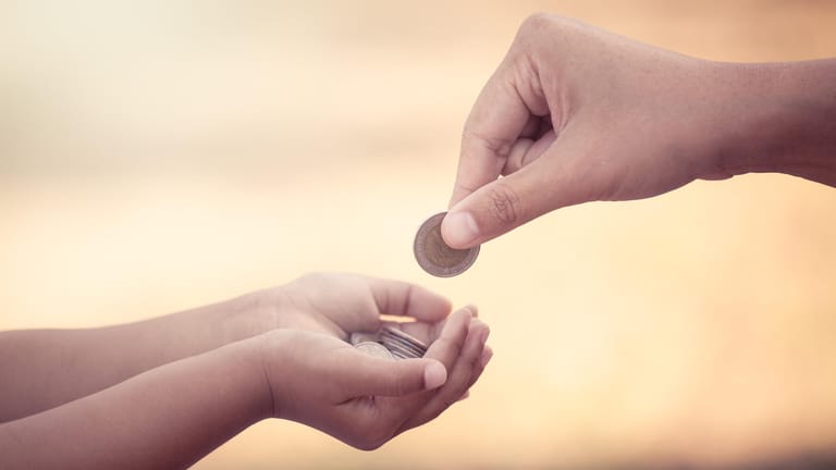 Geldmünzen in Kinderhand: Eltern können sich entscheiden, ob sie entweder Kindergeld beziehen oder sich den Kinderfreibetrag steuerlich anrechnen lassen.