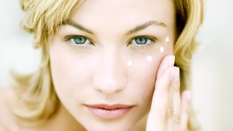 Frau nutzt Antifaltencreme: Besonders um die Augenpartie entstehen mit steigendem Alter schnell Falten.