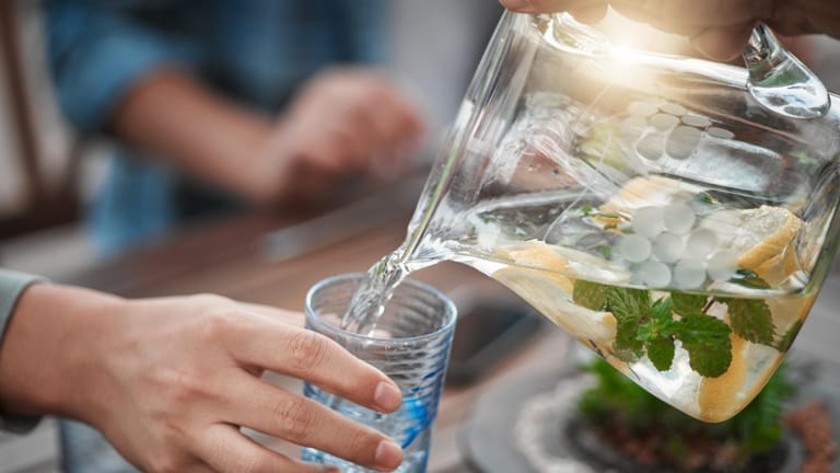 Wasser wird ins Glas gegossen: Auf zuckerhaltige Getränke sollten Sie bei der Paleo-Diät verzichten.