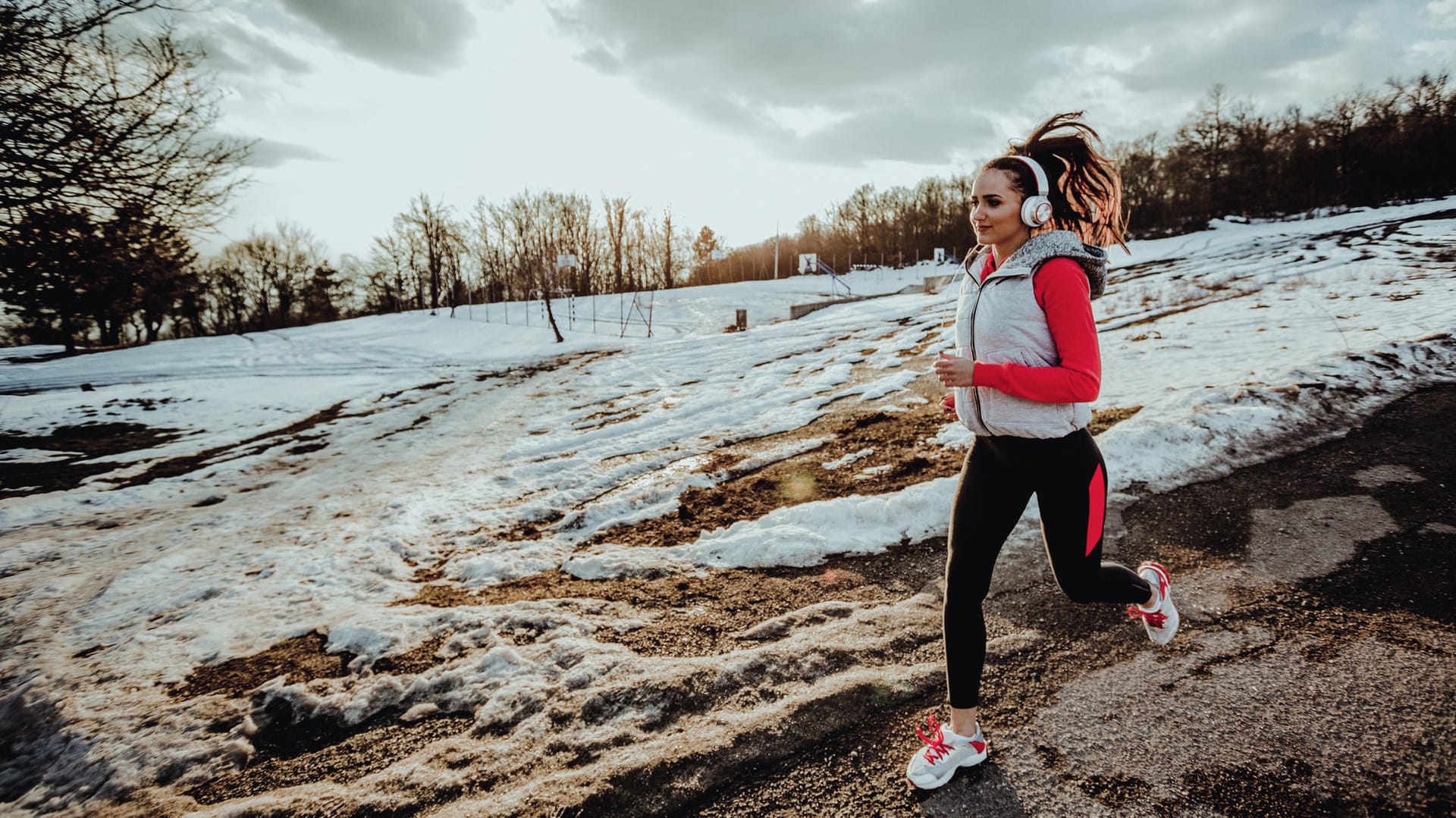 Joggerin mit Kopfhörern: Im Winter draußen Sport zu treiben, kostet viele Menschen einiges an Überwindung.