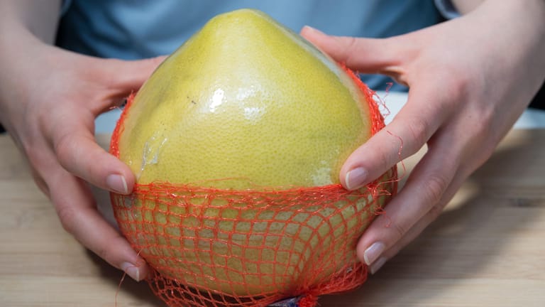 Pomelo im Netz: Vor dem Schälen sollte die Frucht wegen möglicher Pestizidrückstände heiß abgewaschen werden.