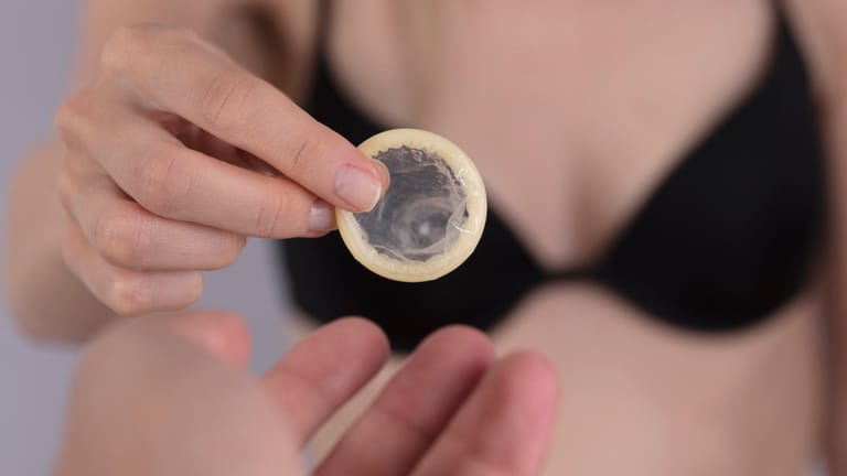 Frau mit Kondom in der Hand: Der beste Schutz vor Chlamydien ist geschützter Geschlechtsverkehr.
