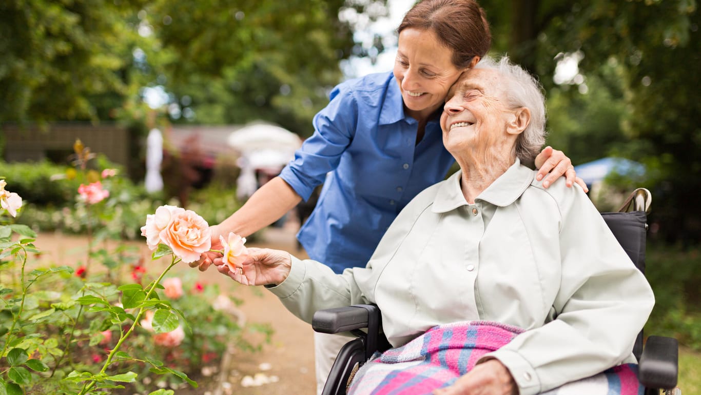 Seniorin mit Pflegerin im Park: Erhöht sich der Pflegegrad, muss der Pflegebedürftige nicht mit einem höheren Eigenanteil an den direkten Pflegekosten rechnen.