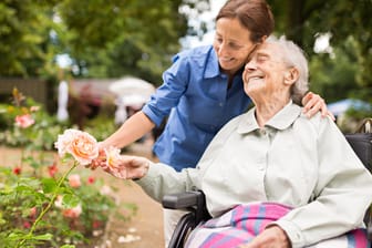 Seniorin mit Pflegerin im Park: Erhöht sich der Pflegegrad, muss der Pflegebedürftige nicht mit einem höheren Eigenanteil an den direkten Pflegekosten rechnen.