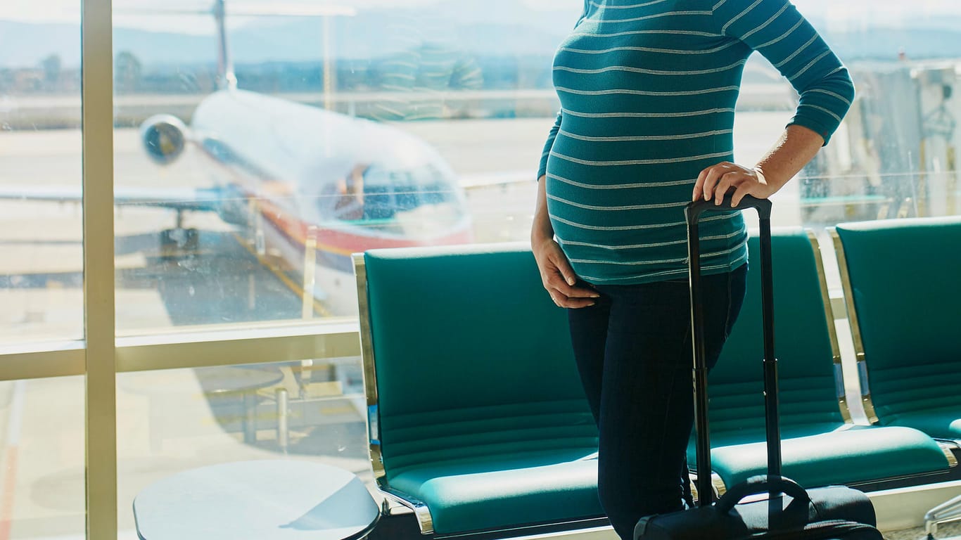 Schwangere an einem Flughafen: Ab der 28. Schwangerschaftswoche benötigen Schwangere meist eine Bescheinigung über ihre Flugtauglichkeit vom Arzt, um Fliegen zu dürfen.