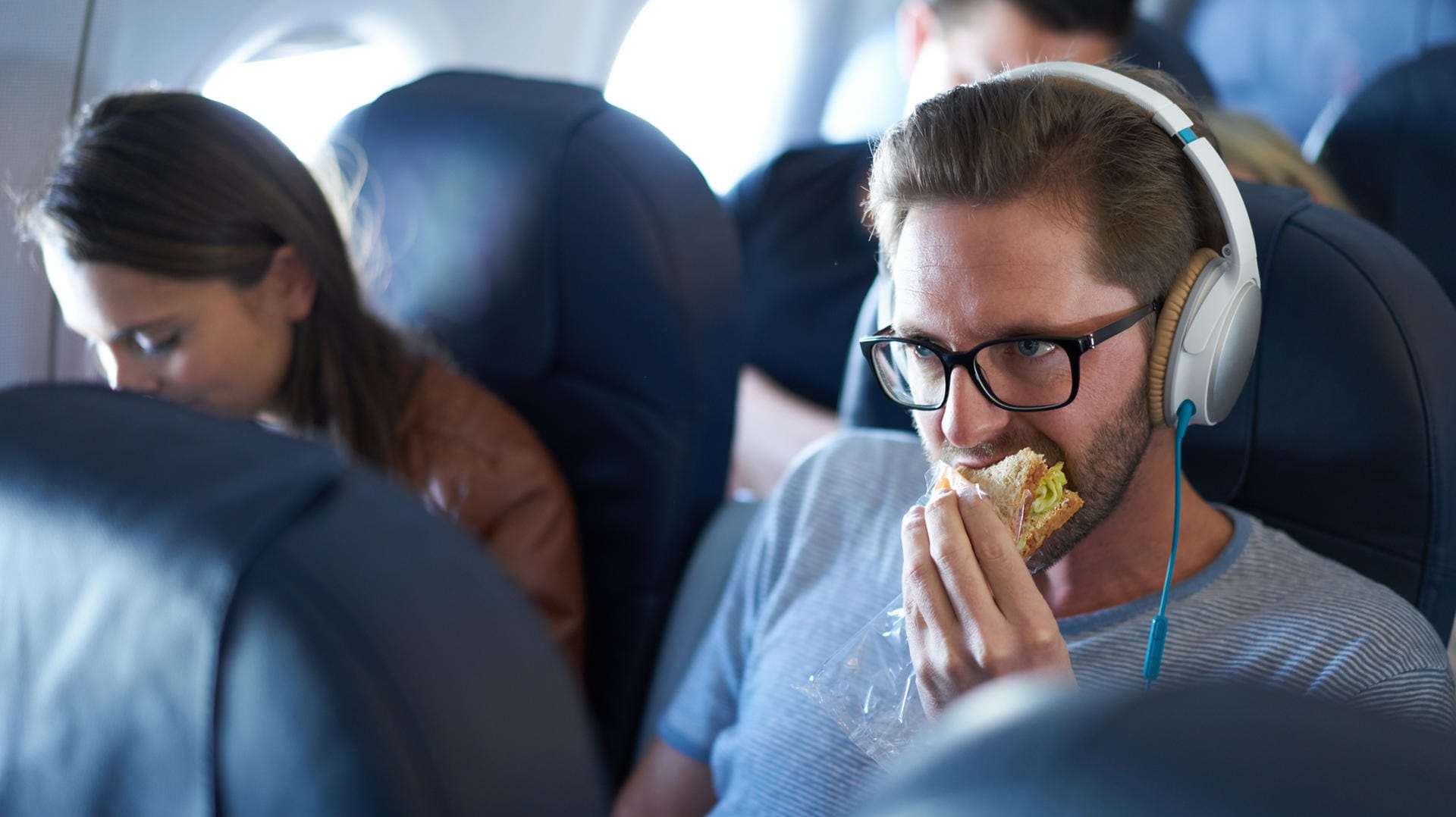 Mann isst Sandwich im Flugzeug: Grundsätzlich sind feste Lebensmittel wie Brot im Flugzeug erlaubt.