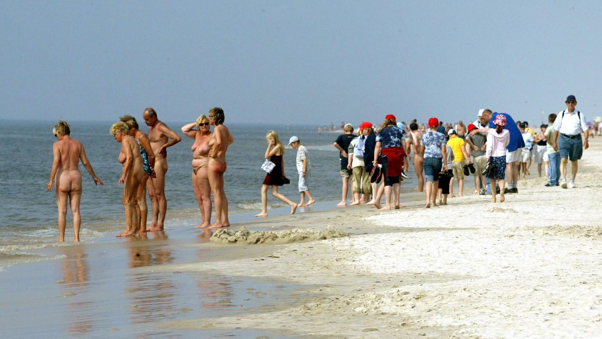 FKK-Urlauber stehen neben angezogenen Touristen: An einigen FKK-Stränden ist Kleidung gänzlich verboten.