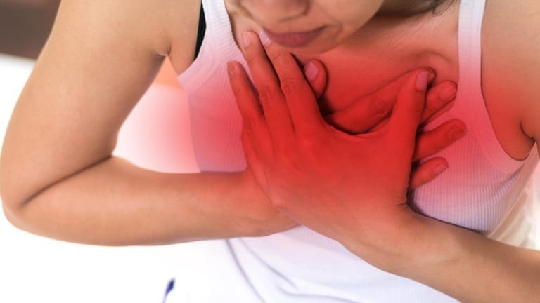 Eine Frau presst die Hände auf die Brust: Schmerzen, Atemnot und Herzrasen sind Alarmzeichen für eine Lungenembolie.