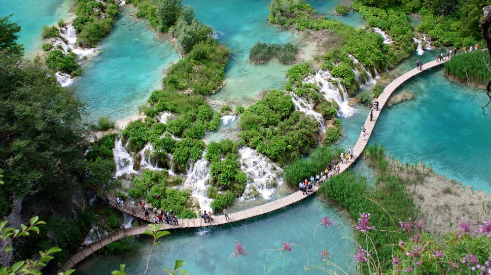 Touristen laufen auf den Holzwegen im Plitvicer Nationalpark: Hauptanziehungspunkt sind die 16 kleinen Seen, die durch Wasserfälle miteinander verbunden sind.