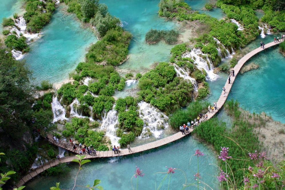 Touristen laufen auf den Holzwegen im Plitvicer Nationalpark: Hauptanziehungspunkt sind die 16 kleinen Seen, die durch Wasserfälle miteinander verbunden sind.