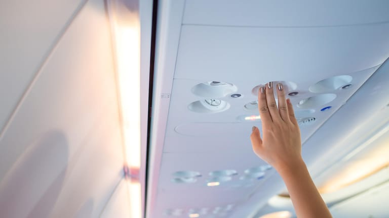 Frau tastet nach der Lüftung im Flugzeug: Über die Klimaanlage können sich Keime verbreiten.